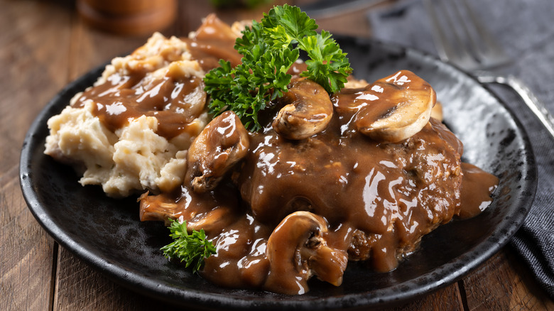Plate of Salisbury steak topped with herb garnish