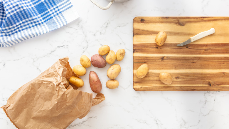 Overhead view of bag of potatoes and cutting board