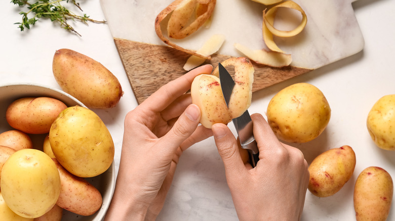 Someone peels a potato