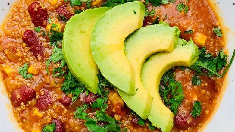 close up of quinoa chili with avocado and cilantro garnish