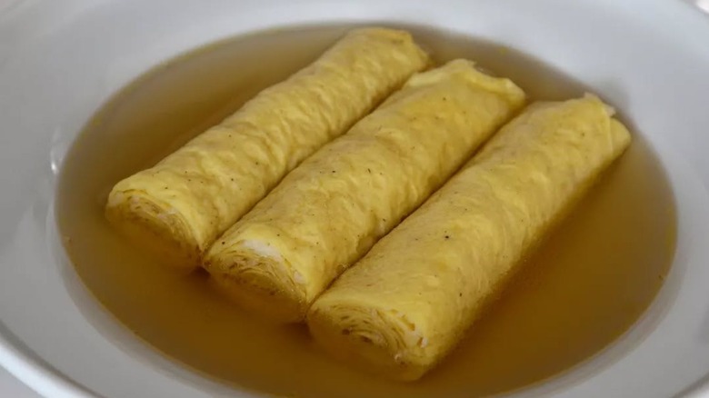Three crepes sit in a bowl of broth.