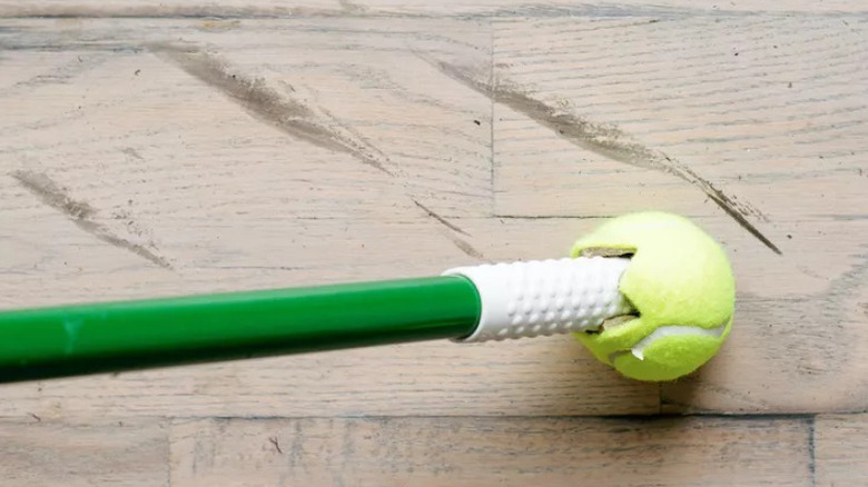 Tennis ball on end of mop handle on floor