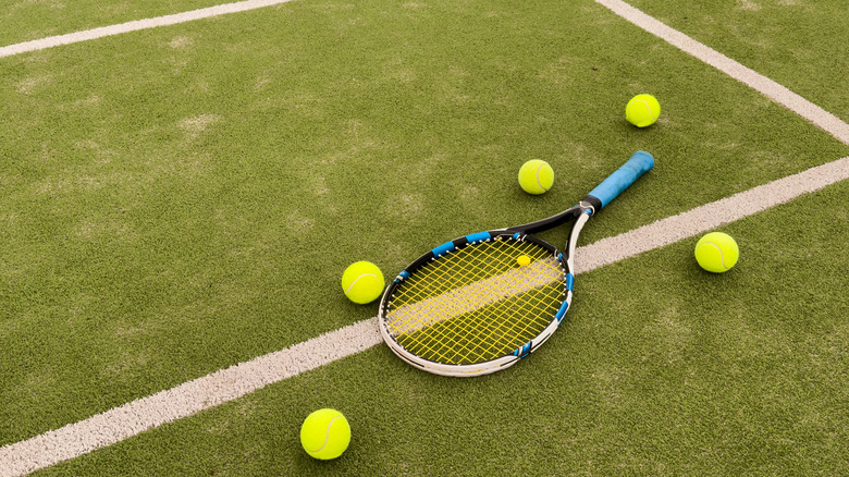 tennis balls on court with racket