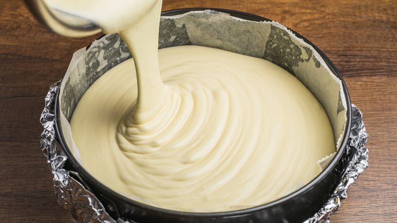 Overhead view of pouring yellow cake batter into cake pan