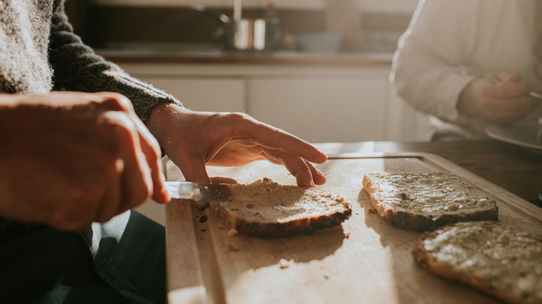 A person spreads butter on bread