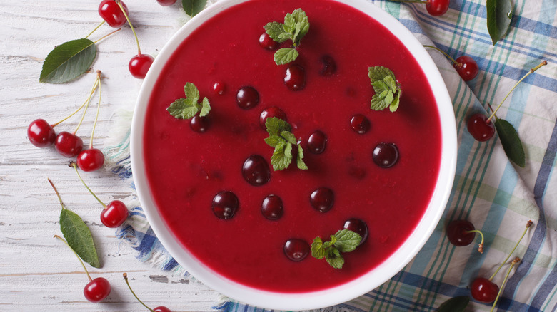 bowl of cherry soup with mint leaves on white table