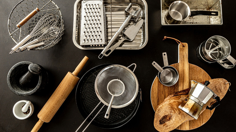 Various metal and wooden kitchen tools displayed on a black surface