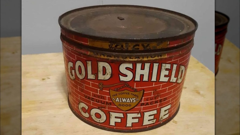 An old tin of Gold Shield coffee on a wooden tabletop