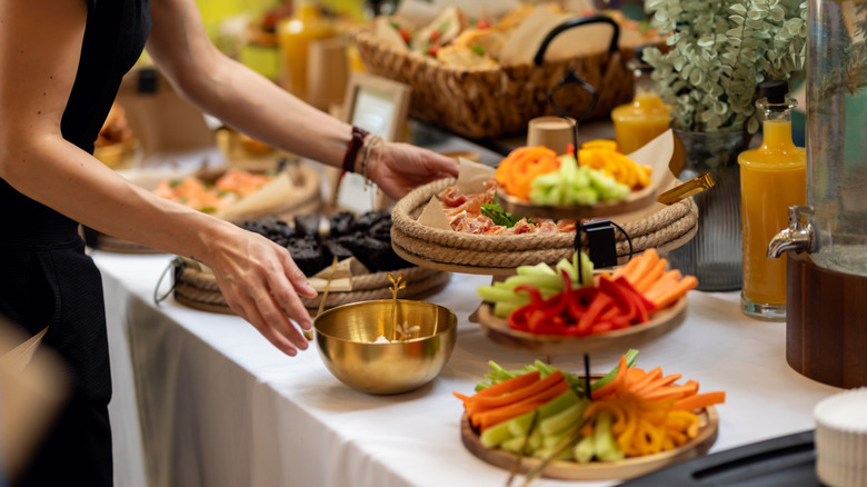 Someone arranging platters of food on a table