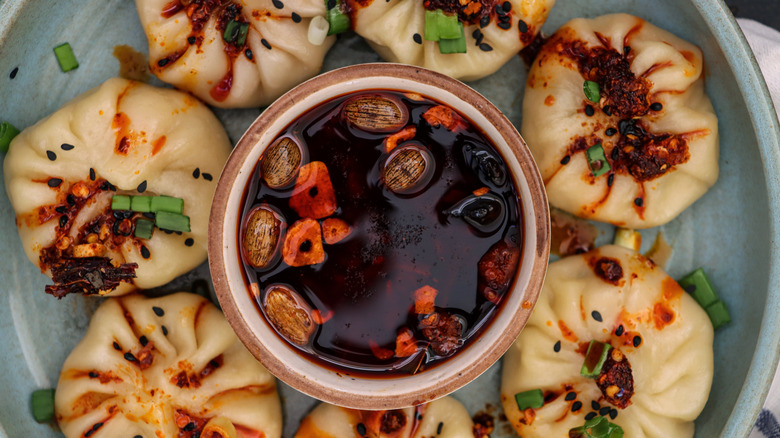 dumplings surrounding a bowl of chili dipping sauce
