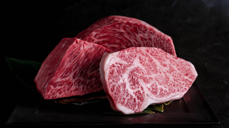 Cuts of raw Wagyu beef on black background