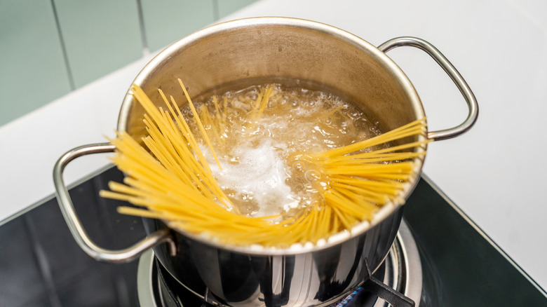 A pot of spaghetti being cooked on a stovetop.