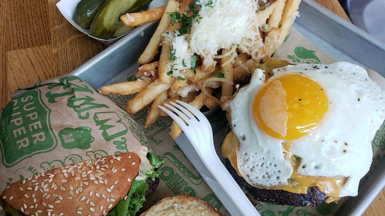 Two Super Duper burgers with cheese fries, sauce, utensils, and homemade pickles
