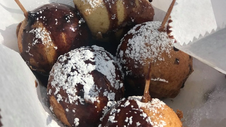 Deep-fried buckeyes with powdered sugar on sticks.