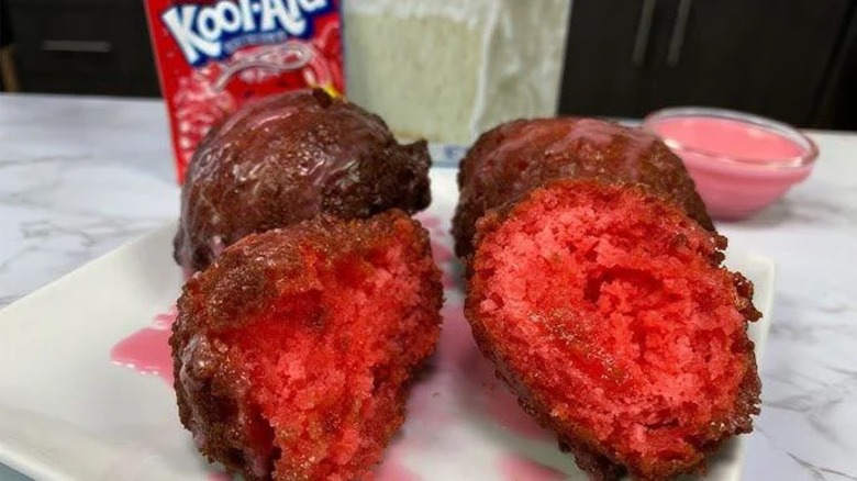 Four pieces of deep-fried Kool-Aid on plate with packet in background.