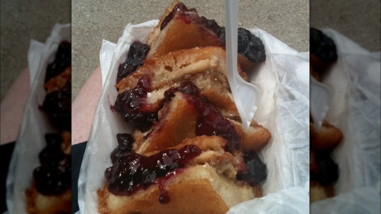 Deep-fried peanut butter and jelly sandwich in tray with plastic fork.