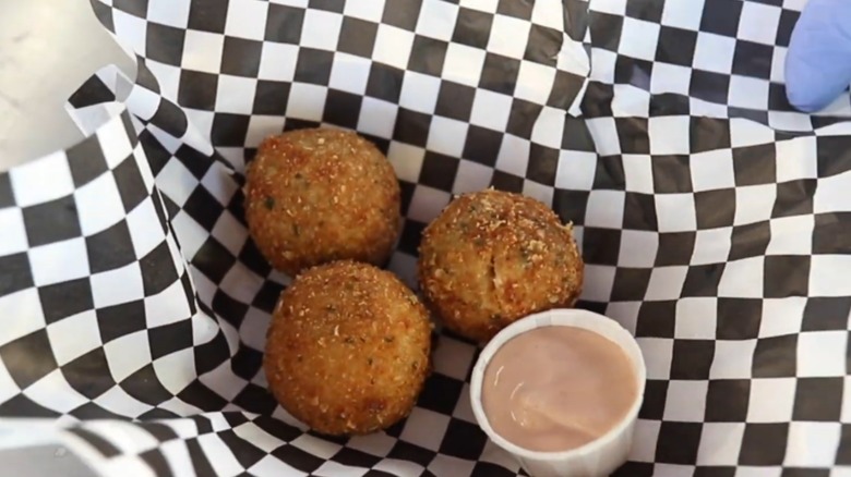 Balls of deep-fried potato salad with dip.
