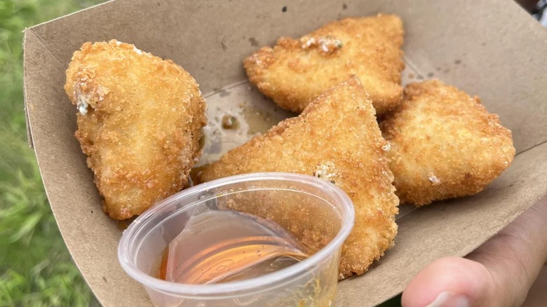 Four pieces of deep-fried ranch in cardboard tray with honey dipping sauce.