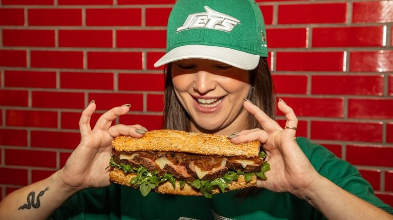A Jets fan holding the premium filet mignon sandwich from Delaware North