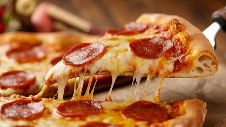 Pepperoni pizza slice being pulled away from the rest of the pizza