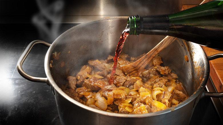 pouring red wine in stew