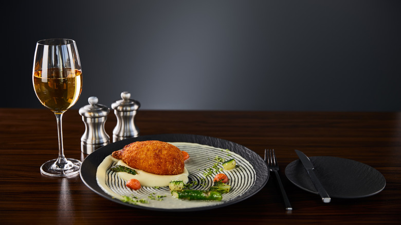 Plate of chicken Kiev with glass of wine