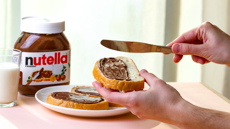 hands spreading nutella on bread