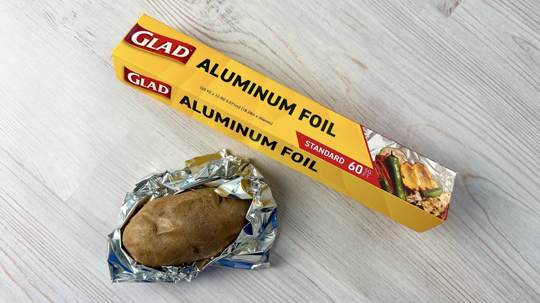 Roll of Glad aluminum foil beside a partially foil-wrapped potato