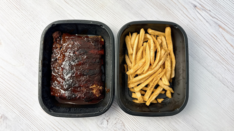To-go containers one with half slab of ribs and one with french fries