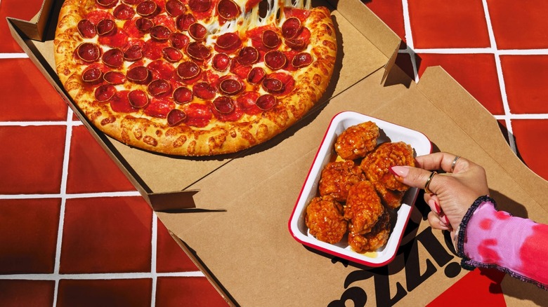 A box of Pizza Hut's pepperoni pizza beside a container of wings