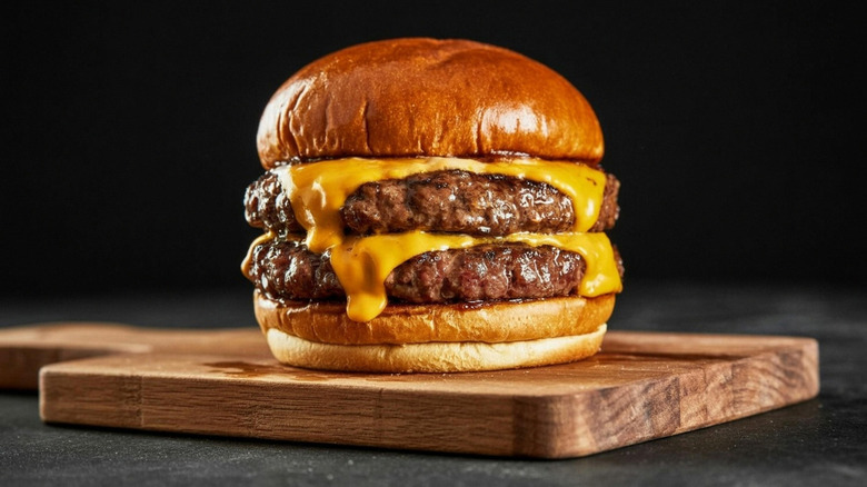Double cheeseburger on a wooden board against a black background