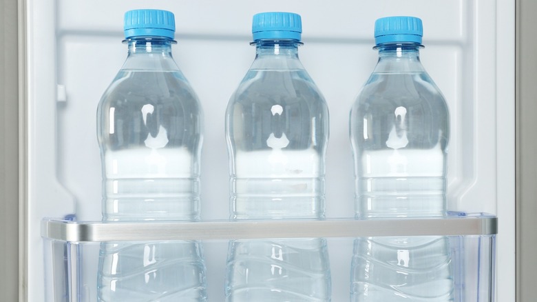 Three water bottles in the door of a refrigerator