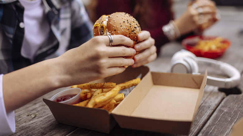 person eating cheeseburger in fast food restaurant