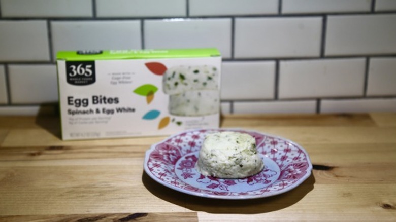 Box of Whole Foods egg white bite and one prepared egg bite on a plate.