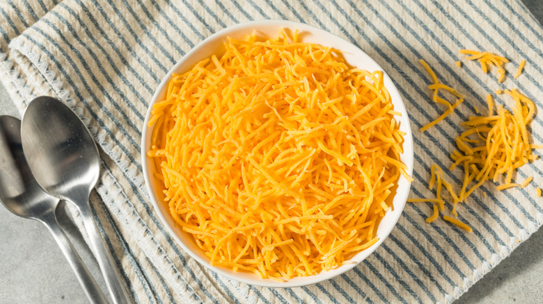 bowl of shredded cheddar cheese on striped napkin