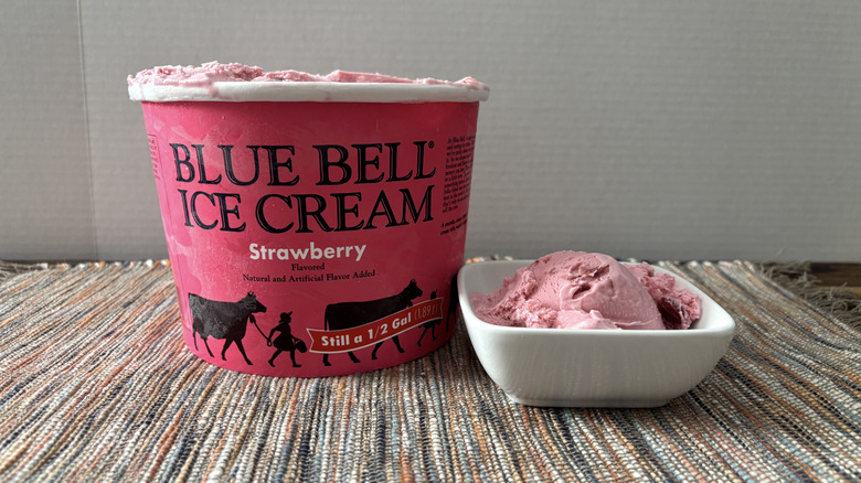 Pint of Blue Bell strawberry ice cream next to square dish with ice cream inside