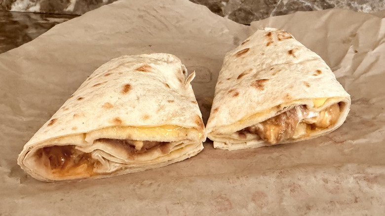 A beefy five layer burrito from Taco Bell cut in half and sitting on its wrapper