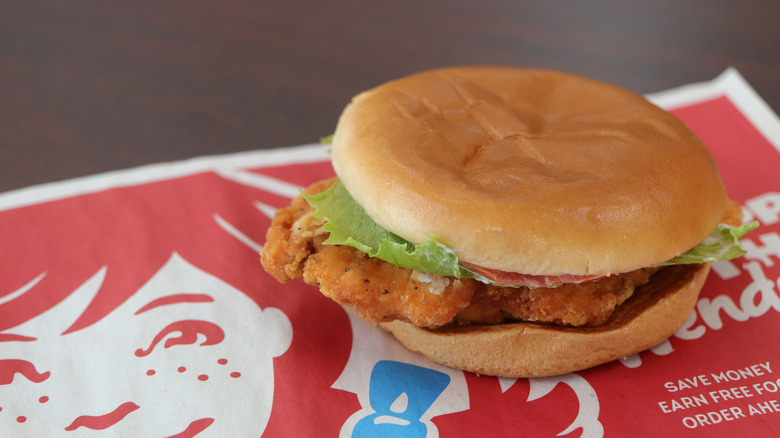 Wendy's chicken sandwich over a paper Wendy's logo