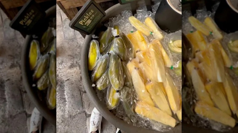 View of pickles and pineapple slices on ice at a cart