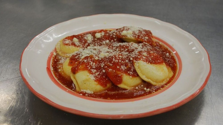 Plate of fresh pasta ravioli with sauce and cheese on a silver table