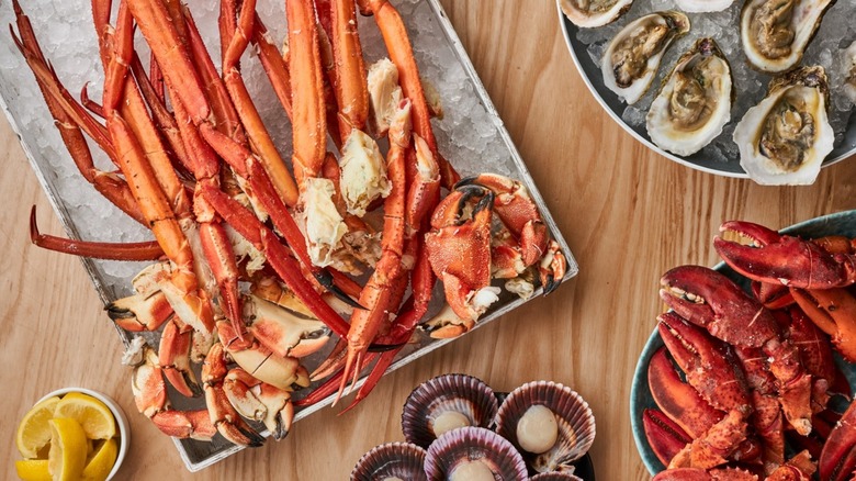 Trays with crab legs, lobster claws, and oysters on wooden table