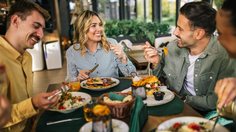 Group of four happy people eating at a restaurant