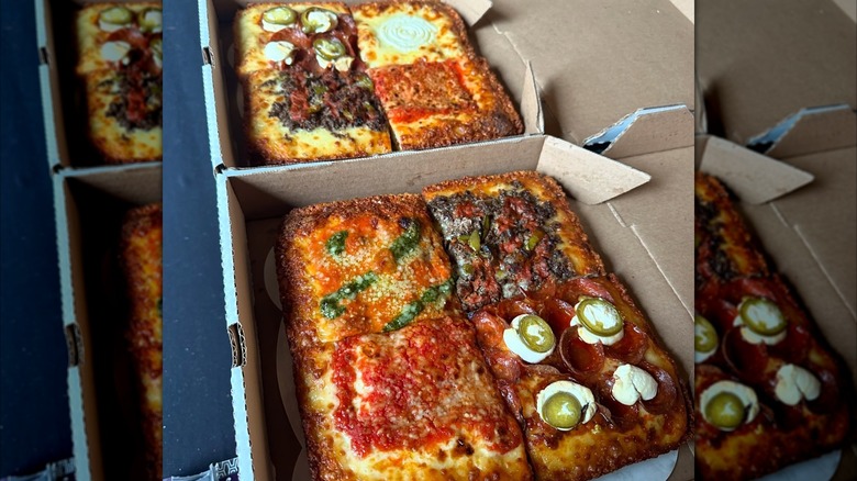 Two Detroit-style pizzas with assorted slices in boxes