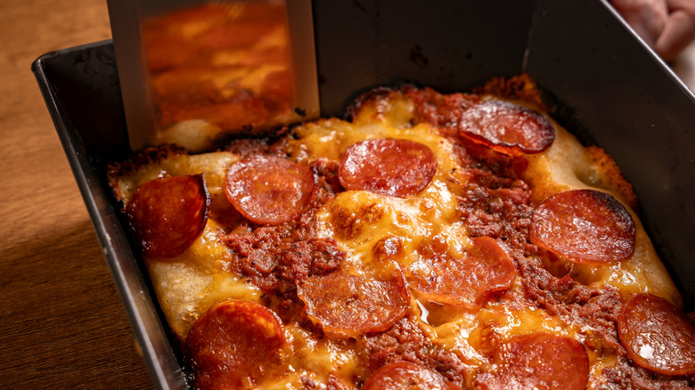 Spatula removing a Detroit-style pizza from a pan