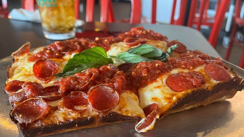 Detroit-style pizza on a table with a drink in the background