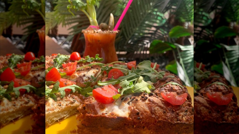 Detroit-style pizza with a bloody mary and palm leaves