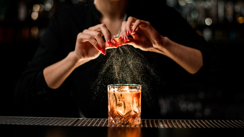 bartender spritzing peel for cocktail