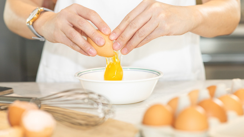 Chef dropping cracked egg in bowl