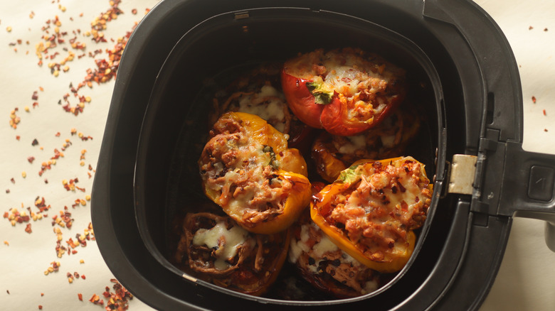 an air fryer cooking basket filled with cooked stuffed bell peppers