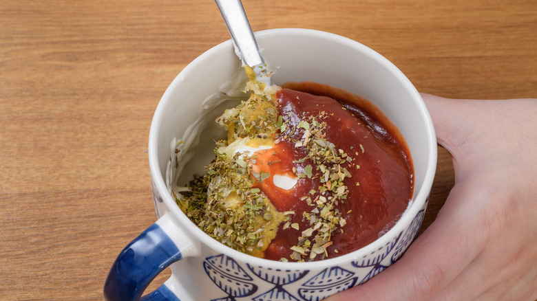hand mixing a marinade with ketchup and seasonings